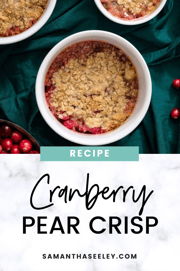 cranberry pear crisp in white ramekin with green cloth background and bowl of cranberries