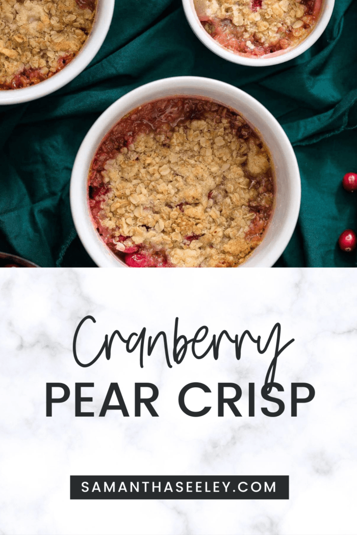 pear cranberry crisp in white ramekin on green background with bowl of cranberries