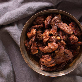 candied pecans and walnuts in a bowl with grey cloth