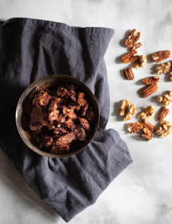 candied pecans and walnuts in a bowl with grey cloth