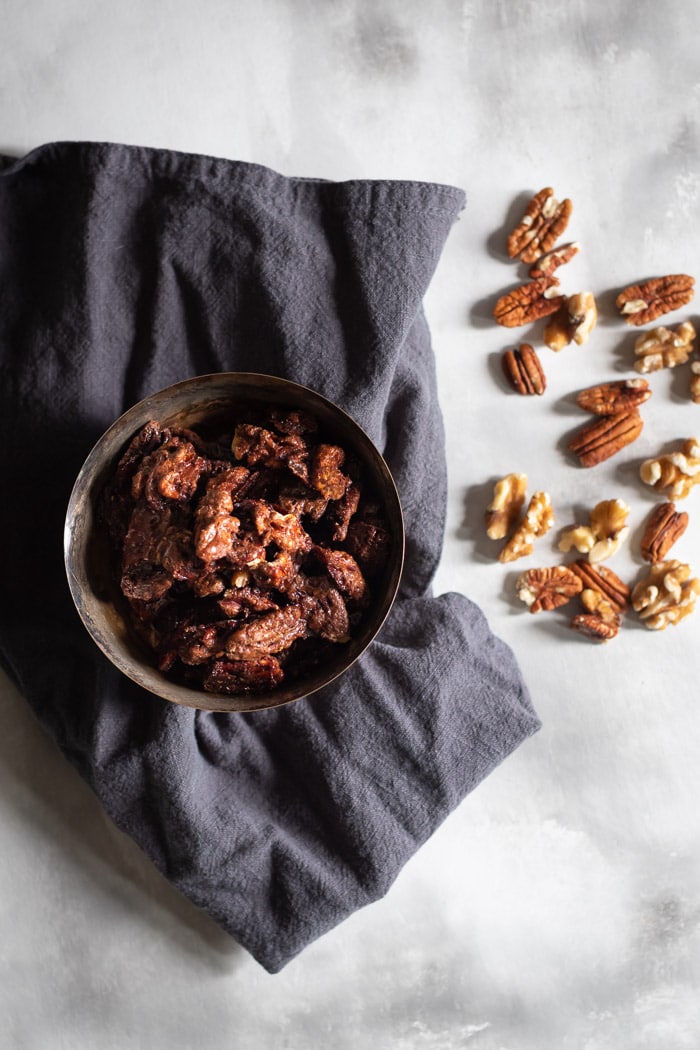 candied pecans and walnuts in a bowl with grey cloth