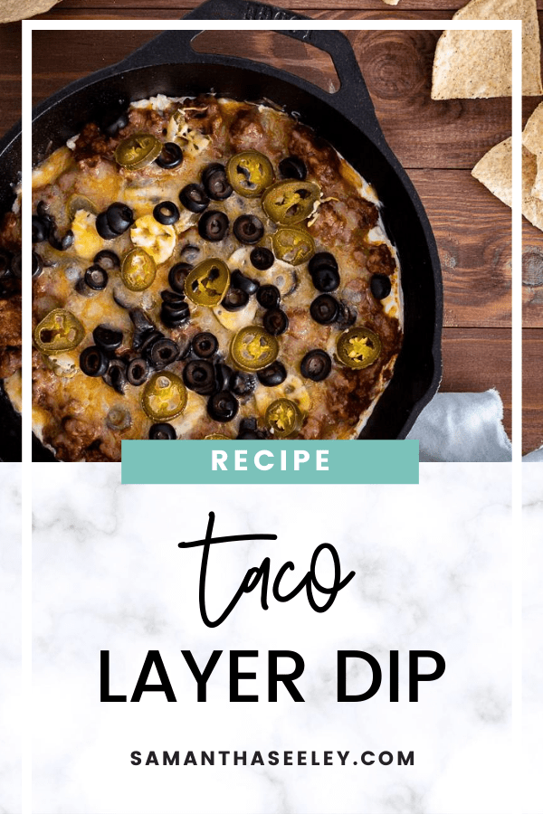 taco layer dip inside cast iron skillet topped with olives and jalapenos