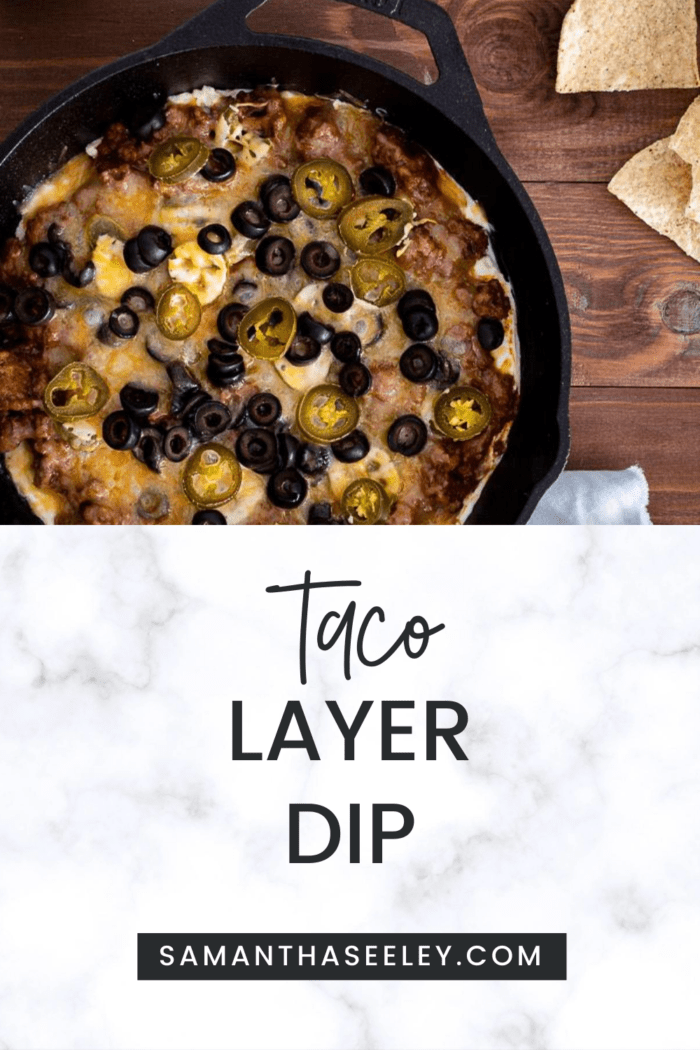 taco layer dip inside cast iron skillet topped with olives and jalapenos