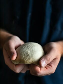 pizza dough being shaped by two hands