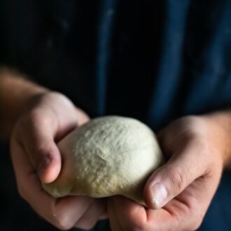 pizza dough being shaped by two hands