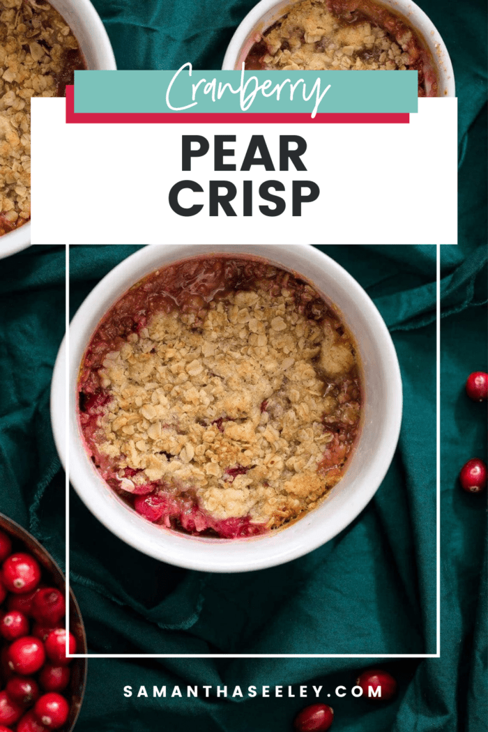 pear cranberry crisp in white ramekin on green background with bowl of cranberries